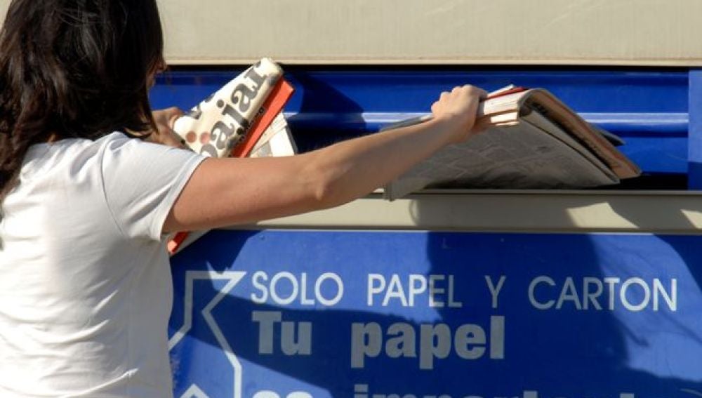 Una persona reciclando papel en el contenedor azul
