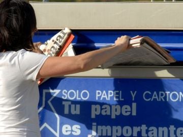 Una persona reciclando papel en el contenedor azul