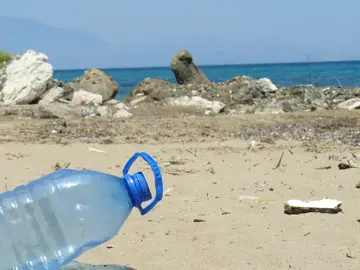 Una botella de plástico junto con otros residuos en una playa Una botella de plástico junto con otros residuos en una playa