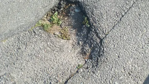Vía con agujeros y desniveles En el trayecto que discurre alrededor de la plaza de Mario Puentes y a lo largo de la vía del mismo nombre así como en la carretera principal del paseo de Patos todo esto situado en el Concello de Nigrán, parroquia de Panxón, playa de Patos, hay unos grandes agujeros en el suelo así como zonas, sobre todo alrededor de la plaza al lado de las tapas de alcantarilla, con grandes desniveles del firme que contribuyen a que se produzcan accidentes sobre todo con motos.