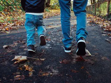 Un niño paseando junto a su padre Un niño paseando junto a su padre