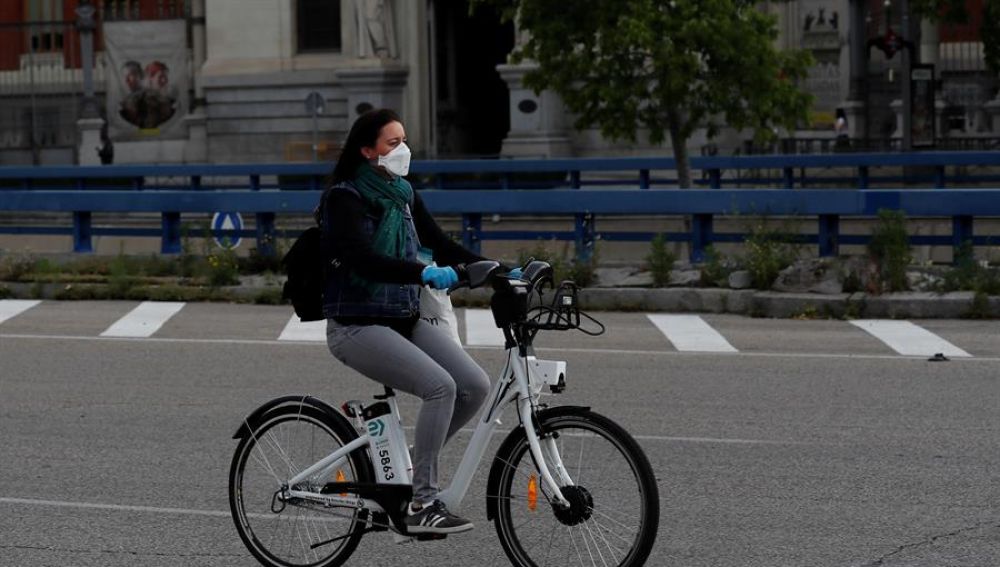 Una mujer con mascarilla y guantes usa una bici de biciMad en Madrid