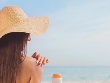 Mujer echándose crema solar en la playa