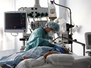 Una médico trata a un paciente de COVID-19 en una UCI. Una médico trata a un paciente de COVID-19 en una UCI.