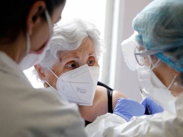 dos sanitarias poniendo una vacuna a una residente de un centro de mayores