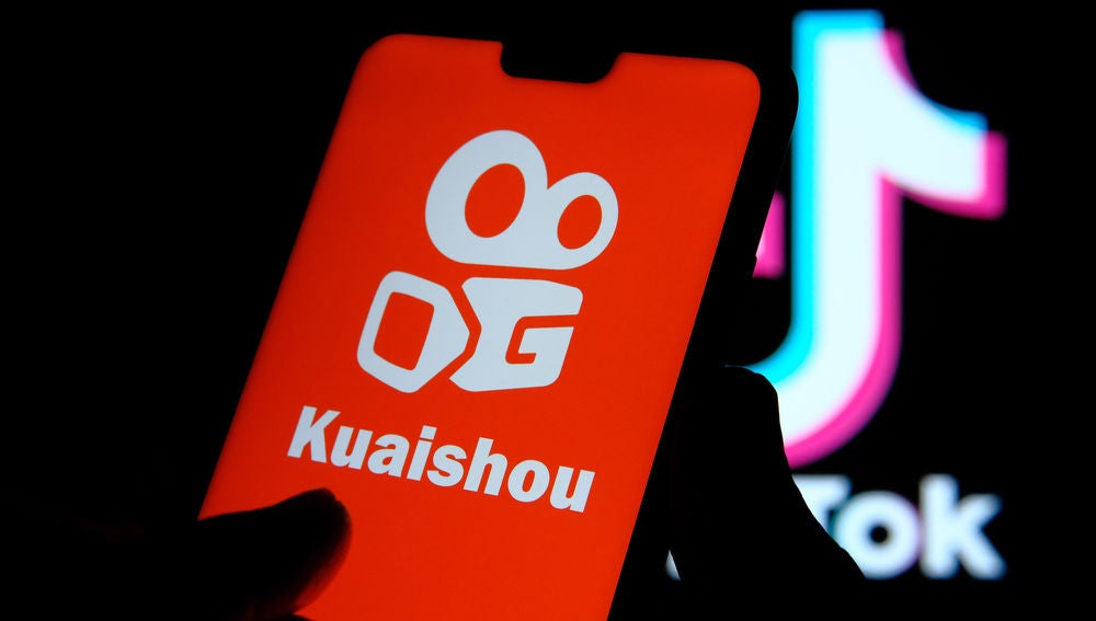 Un móvil muestra la portada de la app Kuaishou, al fondo aparece el logo de Tiktok