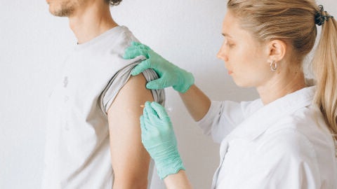 Sanitaria vacuna de la gripe a un hombre joven