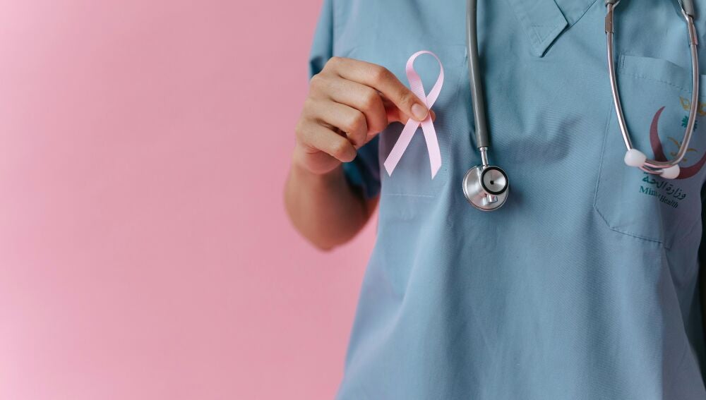 Primer plano de una mano sujetando un lazo rosa, símbolo del cáncer de mama.