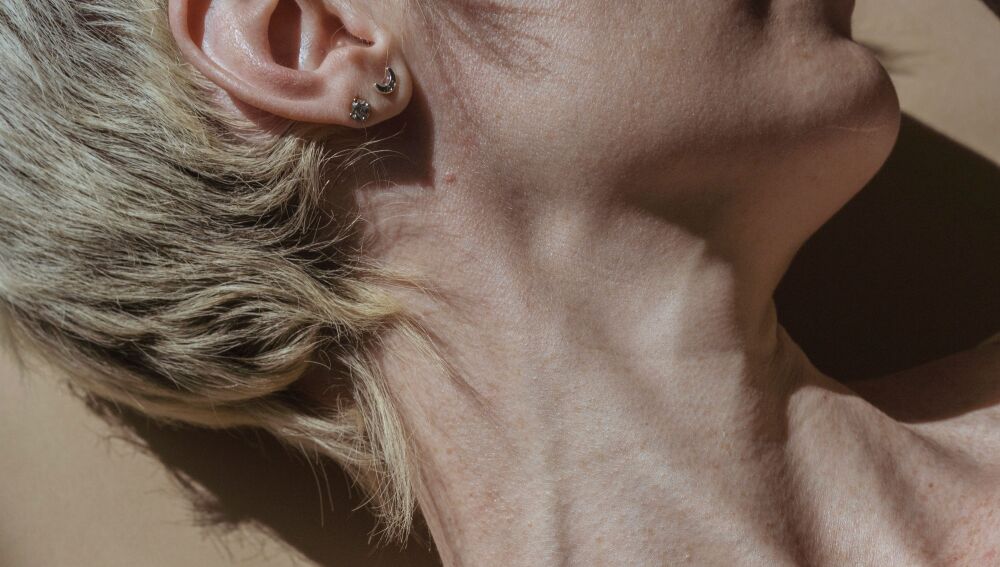 Una toma creativa de estudio que captura la elegancia del cuello y el hombro de una mujer con una iluminación suave.