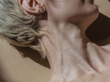 Una toma creativa de estudio que captura la elegancia del cuello y el hombro de una mujer con una iluminaci&oacute;n suave.