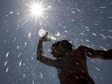 Un trabajador de parques y jardines de Badajoz se refresca bajo un intenso sol