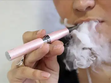 Una mujer fuma un cigarrillo electrónico Una mujer fuma un cigarrillo electrónico