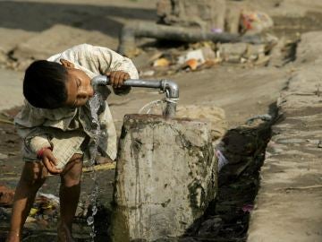 Niño bebiendo agua de una tubería