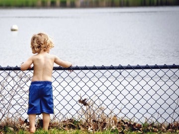 Un niño rubio mira un estanque Un niño rubio mira un estanque