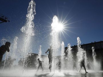Un grupo de niños se refresca en una fuente de Pamplona