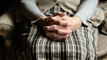 Una persona mayor se agarra las manos Una persona mayor se agarra las manos