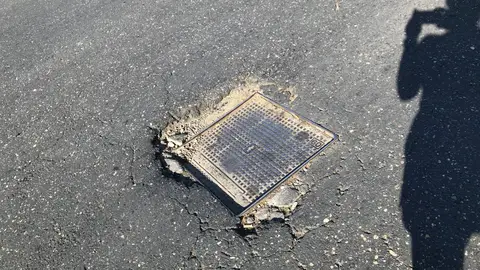 tapa de registro en la calzada en el cruce de las calles Aquitania con carretera de Canillejas a Vicalvaro, se encuentra una tapa de registro en muy mal estado