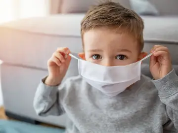 Niño poniéndose mascarilla Niño poniéndose mascarilla