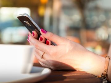 Imagen de una mujer usando un teléfono móvil en un bar