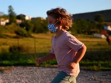 Un niño con mascarilla juega en la calle Un niño con mascarilla juega en la calle