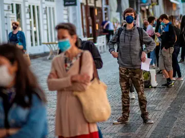 Una cola de gente con mascarillas en una calle de Italia Una cola de gente con mascarillas en una calle de Italia