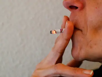 Una mujer termina de fumarse un cigarro Una mujer termina de fumarse un cigarro