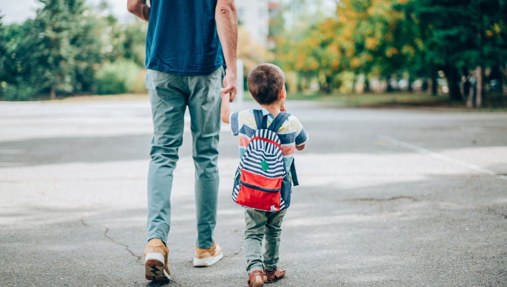 Un padre camina con su hijo en dirección al colegio
