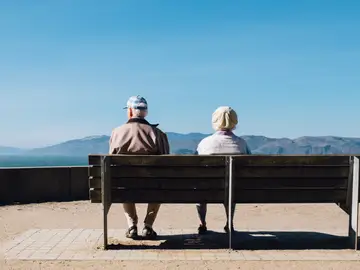 Dos ancianos sentados en un banco mirando hacia el horizonte costero Dos ancianos sentados en un banco mirando hacia el horizonte costero