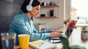 Una mujer teletrabaja desde su casa con los auriculares puestos Una mujer teletrabaja desde su casa con los auriculares puestos