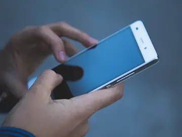 Foto de archivo de una persona usando un teléfono móvil Foto de archivo de una persona usando un teléfono móvil