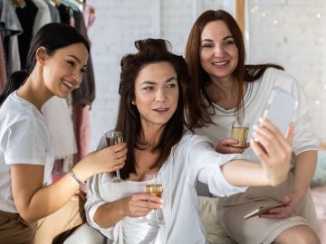 Mujeres se hacen un selfie con una copa de champán.
