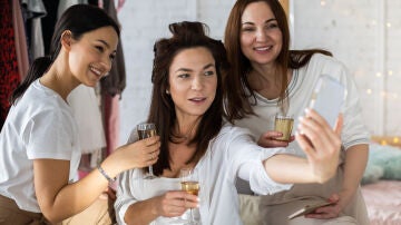 Mujeres se hacen un selfie con una copa de champán.