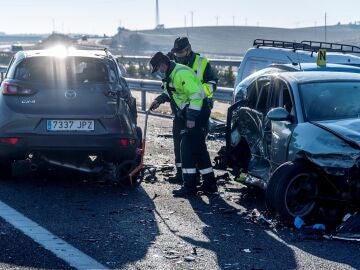 Agentes de la Guardia Civil revisan dos coches involucrados en un accidente de carretera