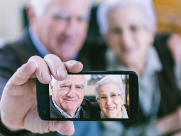 Dos personas mayores muestran una imagen tomada con su móvil.