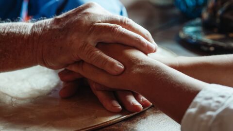 Manos de persona mayor y persona joven entrelazadas