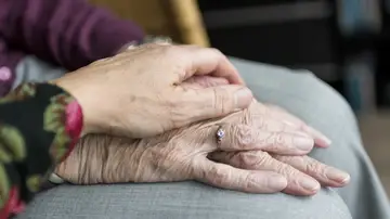 una mano anciana cogida por un sanitario una mano anciana cogida por un sanitario