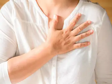 Una mujer con la mano en el pecho. El dolor en el pecho es el síntoma más común del infarto en hombres y en mujeres Una mujer con la mano en el pecho. El dolor en el pecho es el síntoma más común del infarto en hombres y en mujeres